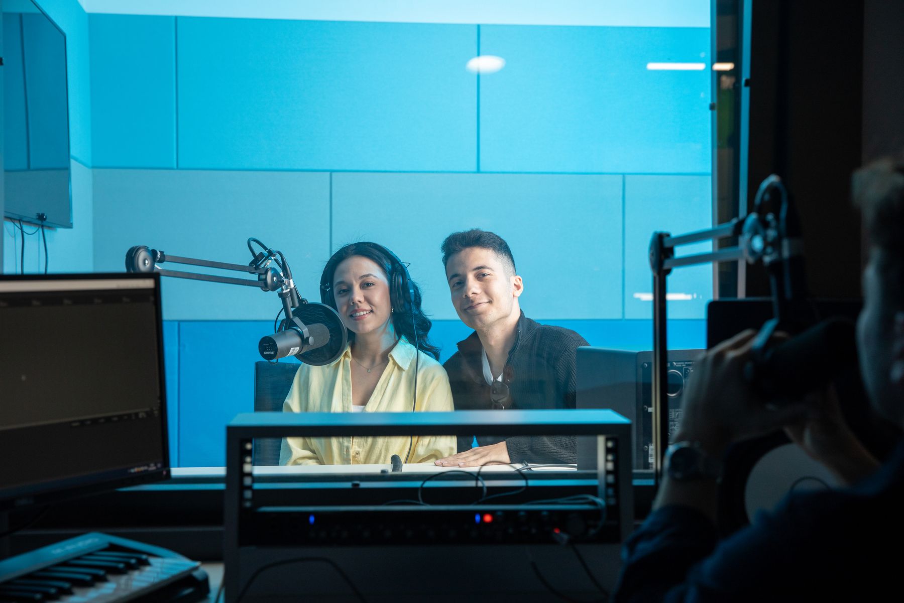 Two presenters working in a professional radio studio with broadcast microphones